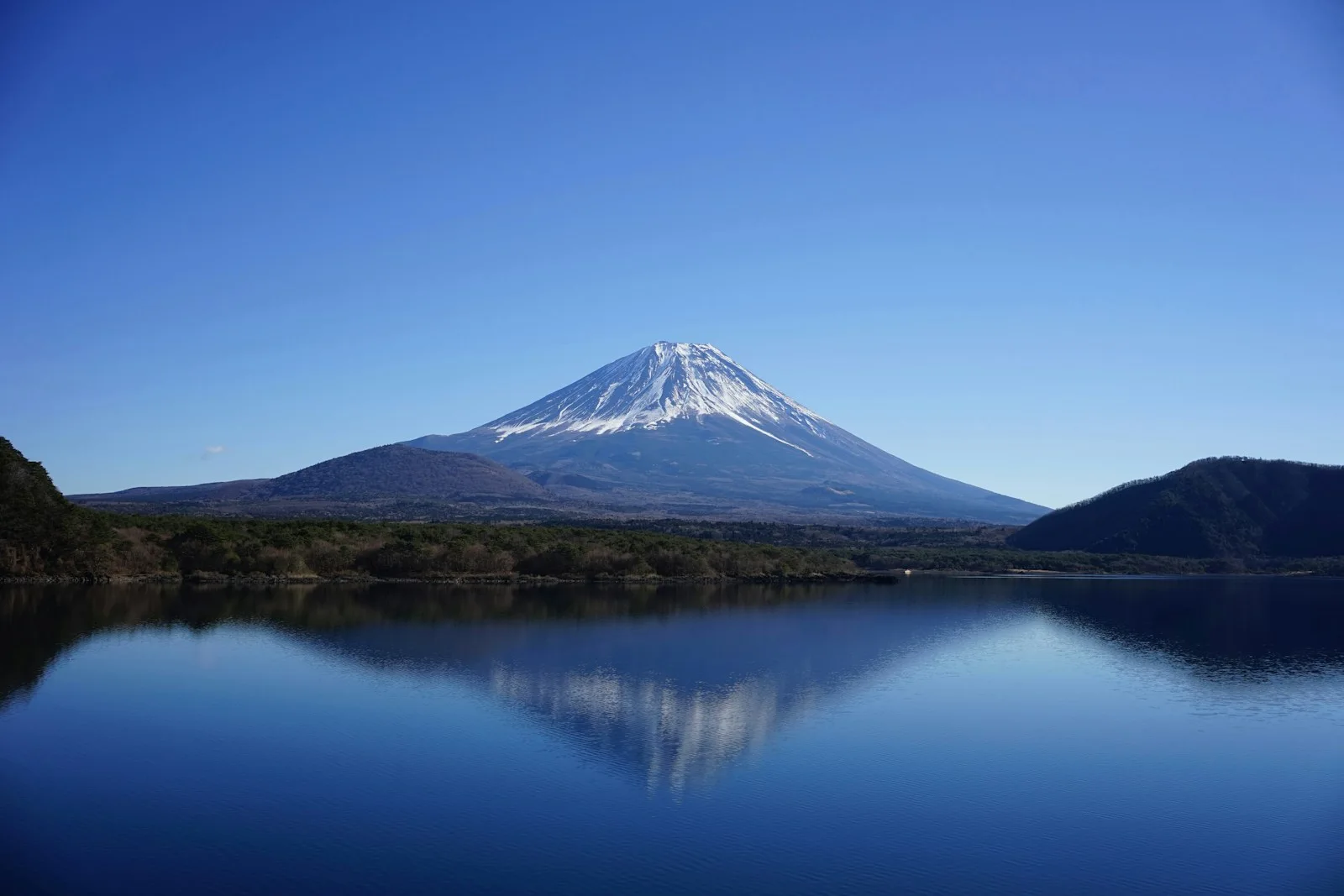 Monte Fuji coberto de neve refletido em um lago azul